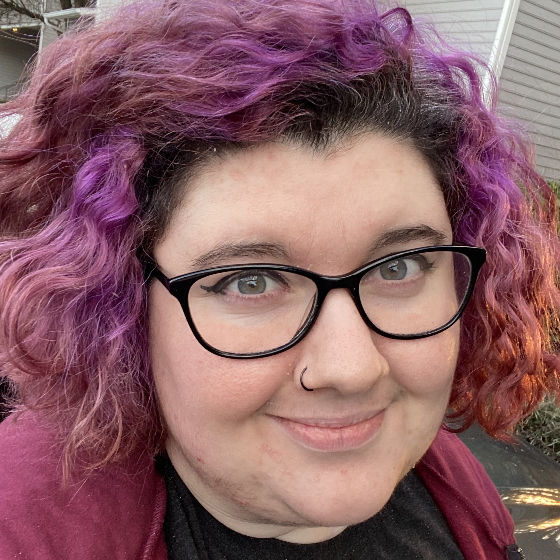 Picture of a person with glasses and purple curly hair